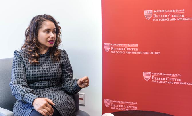 Desirée Cormier Smith seated and speaking at left and a crimson banner with the Belfer Center world mark at right. 