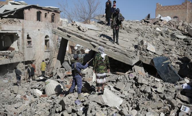 People inspect the wreckage of buildings that were damaged by Saudi-led coalition airstrikes, in Sanaa, Yemen, Tuesday, Jan. 18, 2022.