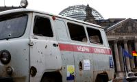 A damaged Ukrainian ambulance with holes caused by cluster bombs' shrapnel stands in front of the Reichstag building.
