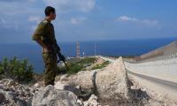 An Israeli soldier stands near the fence on the Israeli border with Lebanon 