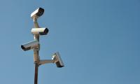 surveillance cameras on post against blue sky